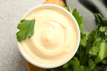 Delicious mayonnaise sauce in bowl with parsley on grey table, top view