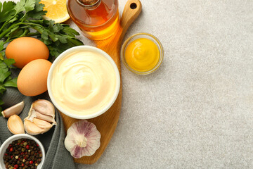 Delicious mayonnaise sauce in bowl and ingredients on grey table, flat lay. Space for text