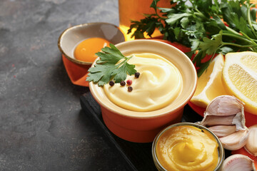 Delicious mayonnaise sauce in bowl and ingredients on grey table, closeup