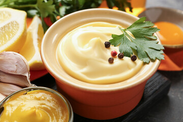 Delicious mayonnaise sauce in bowl and ingredients on grey table, closeup