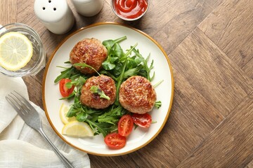 Delicious patties with greens, tomatoes, ketchup and drink on wooden table, flat lay. Space for text