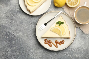 Pieces of delicious lemon cheesecake served on grey textured table, flat lay. Space for text