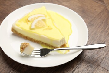 Piece of delicious cheesecake with lemon curd on wooden table, closeup