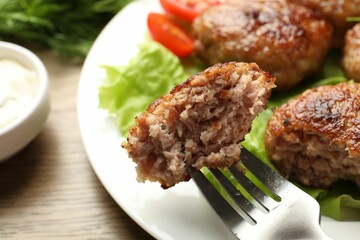 Eating delicious patty at wooden table, closeup