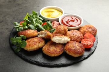 Tasty patties, tomato, spinach, mustard and ketchup on grey textured table, closeup