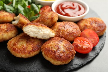 Tasty patties and tomato on grey table, closeup