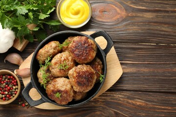 Tasty patties, dill in frying pan, mustard and peppercorns on wooden table, flat lay. Space for text