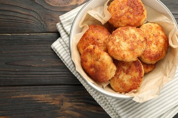 Tasty patties in bowl on wooden table, top view. Space for text
