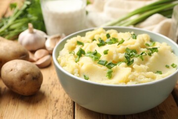 Delicious mashed potato with green onions on wooden table, closeup