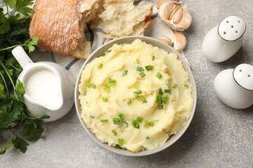 Delicious mashed potato with green onions served on grey table, flat lay