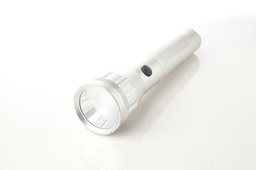 Sleek Silver Flashlight Resting on a Reflective Surface in a Well-Lit Environment