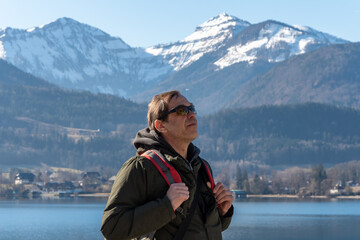 An elderly hiker enjoys nature on a cold day by the lake