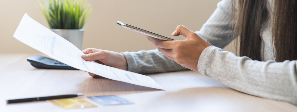 Bill pay concept. Online internet banking asian young woman hand holding invoice use mobile smart phone spend scan barcode to transfer to pay money of credit card without cash. Technology of financial