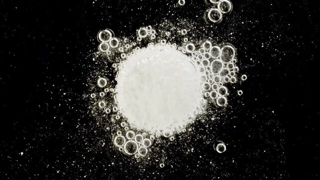Close-up effervescent tablet vitamin, white pill dissolves with bubbles, round bubbling aspirin in water, slow motion. High quality 4k footage