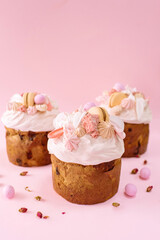 Traditional Ukrainian easter bread or sweet paska bread with topping and decorated with meringue, macarons and eggs isolated on pink background 