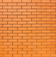 Close-up view of a brick wall with uniform, orange-brown bricks arranged in a classic running bond pattern