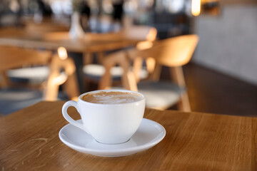 Cup of aromatic coffee on wooden table in cafe, closeup. Space for text
