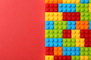 Construction toy. Colorful building bricks on red background, top view with space for text