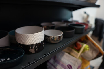 Different feeding bowls on shelf in pet shop, closeup