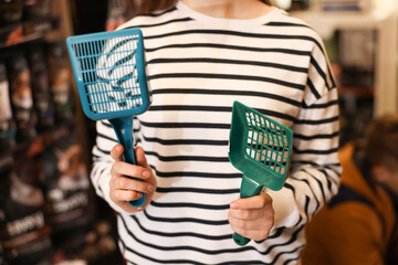 Woman with litter scoops in pet shop, closeup