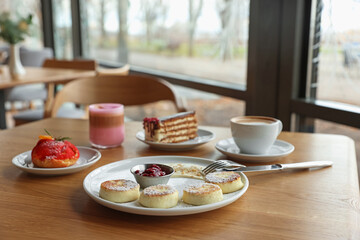 Delicious cottage cheese pancakes, desserts and aromatic coffee served on wooden table in cafe