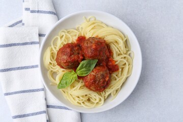 Delicious pasta with meatballs in bowl on light table, top view
