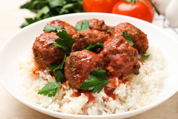 Delicious meatballs with rice, sauce and parsley on light wooden table, closeup