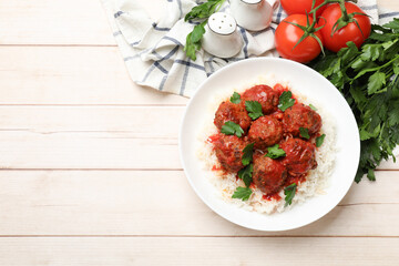 Delicious meatballs with rice, sauce and parsley on light wooden table, flat lay. Space for text