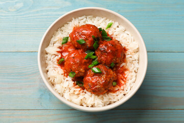 Tasty meatballs with sauce and rice on light blue wooden table, top view