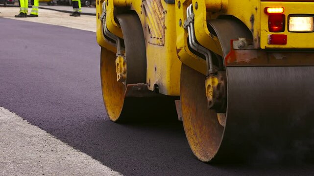 Asphalt Paving. Road Roller Drives Over Hot, Steaming, Freshly Layed Asphalt. Road Roller, Roller-compactor or Roller is a Compactor-type Engineering Vehicle Used to Compact Asphalt.