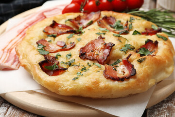 Delicious focaccia bread with bacon and parsley on wooden table, closeup
