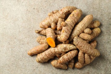 Pile of tumeric rhizomes on grey table, top view. Space for text