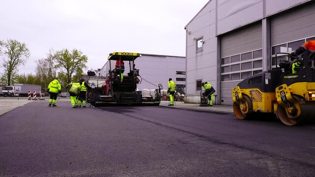Asphalt Paving Machine, Road Roller and Workers Working. Asphalt Concrete or Asphalt, Blacktop, or Pavement in North America, and Tarmac or Bitumen Macadam in the United Kingdom
