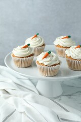 Delicious carrot cupcakes on white marble table against grey background