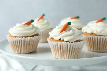 Delicious carrot cupcakes on stand against grey background, closeup