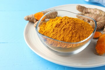 Aromatic turmeric powder in bowl and fresh roots on light blue wooden table, closeup
