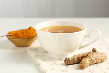 Aromatic turmeric tea, powder and rhizomes on white table, closeup