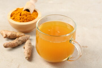 Aromatic turmeric tea, rhizomes and powder on white textured table, closeup