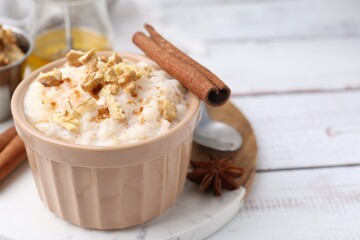 Tasty rice pudding with cinnamon served on white wooden table, closeup. Space for text