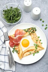 Delicious crepe with egg, bacon, arugula and green peas on grey table, flat lay