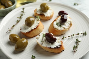 Delicious sandwiches with cream cheese and marinated olives on light table