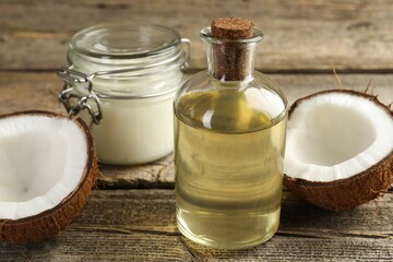 Organic coconut cooking oil and halves of fruit on wooden table, closeup