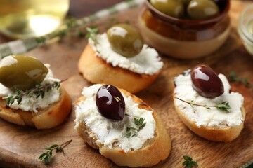 Delicious sandwiches with cream cheese and marinated olives on wooden table