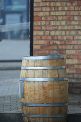 Naklejka premium Wooden barrel for whiskey or wine close-up in the open space against the background of a brick wall.