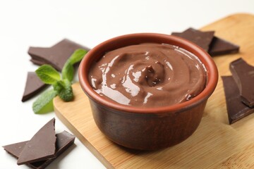 Tasty pudding, mint and pieces of chocolate on white table, closeup