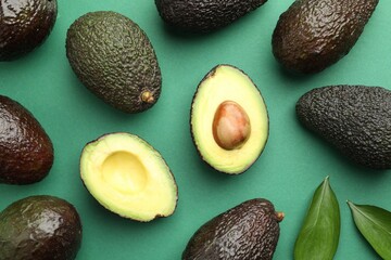 Fresh ripe avocados and leaves on teal background, flat lay