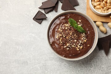 Delicious chocolate mousse in bowl and ingredients on grey table, flat lay. Space for text