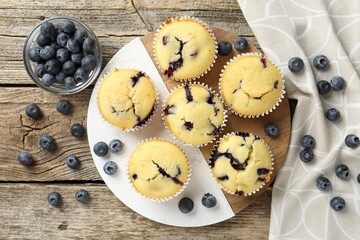 Delicious muffins with blueberries on wooden table, flat lay