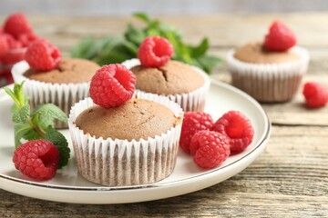 Delicious muffins with raspberries and mint on wooden table, closeup