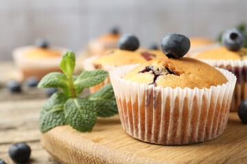 Delicious muffins with blueberries and mint on wooden table, closeup